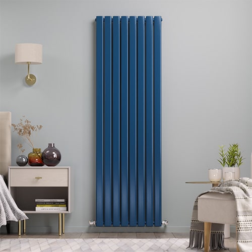A tall blue aruba vertical designer radiator on a blue wall in a bedroom